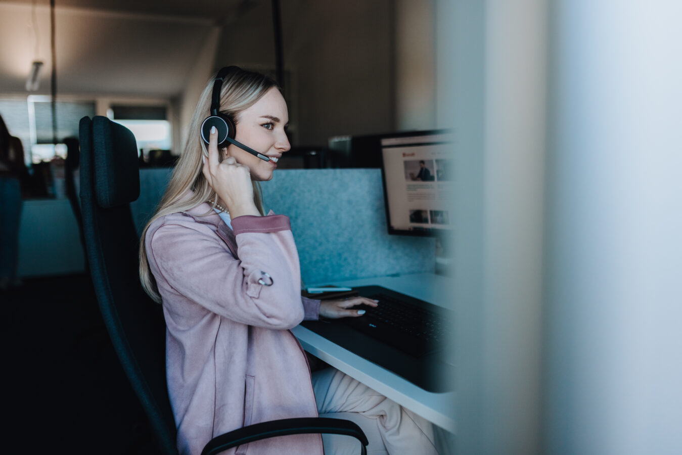 Frau sitzt mit Headset vor dem Laptop